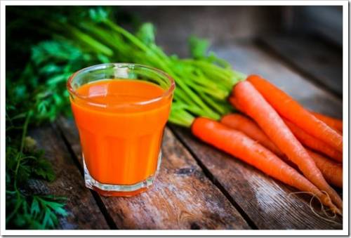 Fresh-squeezed carrot juice on wooden background