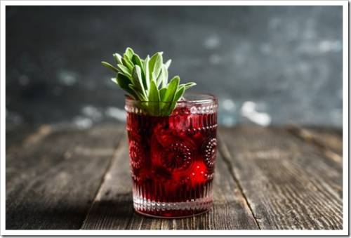 Gin based sweet old-fashioned cocktail with cherry and sage on the rustic background. Selective focus. Shallow depth of field.