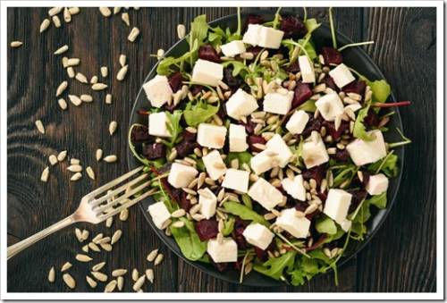 Healthy beetroot salad with feta cheese, arugula and sunflower seeds.