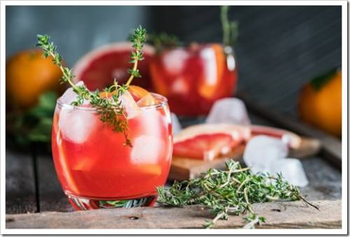 Grapefruit, thyme and ice cocktail. Refreshing drink on rustic background, close-up.