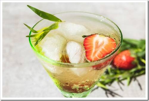 refreshing summer cocktail drink lemonade with ice, strawberries and tarragon in a glass